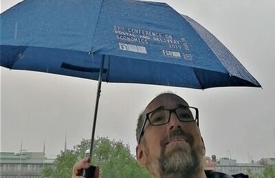 Team member standing in the rain with a conference umbrella