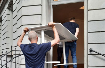 Menschen schleppen ein Tisch ins neue Büro