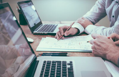 Des personnes discutant devant 2 ordinateurs portables